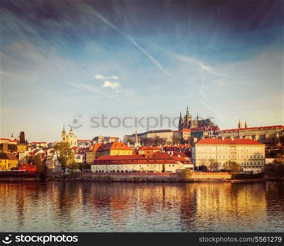 Vintage retro hipster style travel image of Gradchany (Prague Castle) and St. Vitus Cathedral over Vltava river on sunset