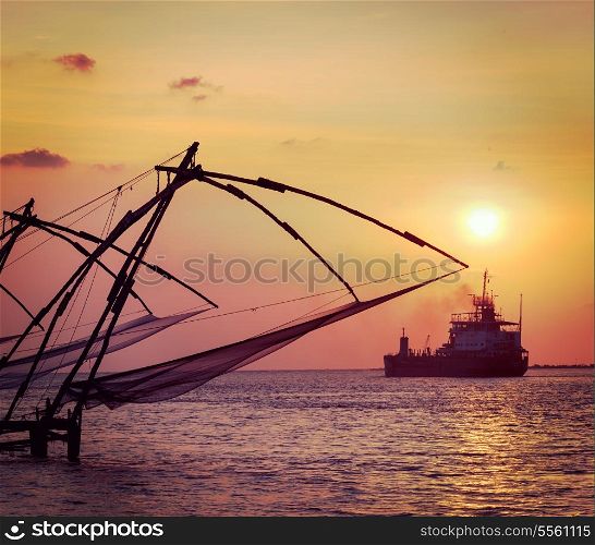 Vintage retro hipster style travel image of Kochi chinese fishnets on sunset and modern ship. Fort Kochin, Kochi, Kerala, India