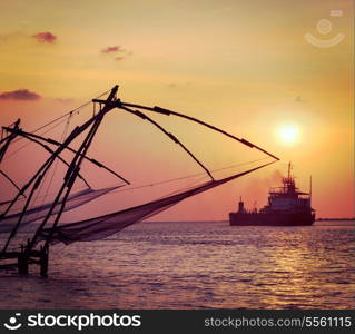 Vintage retro hipster style travel image of Kochi chinese fishnets on sunset and modern ship. Fort Kochin, Kochi, Kerala, India