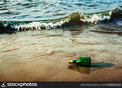 Vintage retro hipster style travel image of message bottle on beach sand in waves