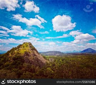 Vintage retro hipster style travel image of sky above small mountains, covered with trees with grunge texture overlaid. Sri Lanka