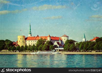 Vintage retro hipster style travel image of View of Riga Castle over Daugava river with grunge texture overlaid. Riga, Latvia