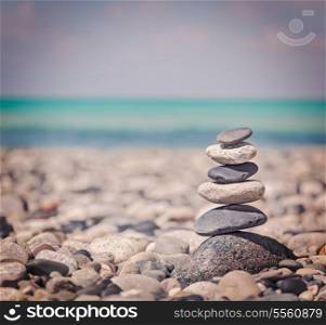 Vintage retro hipster style travel image of Zen meditation background - balanced stones stack close up on sea beach