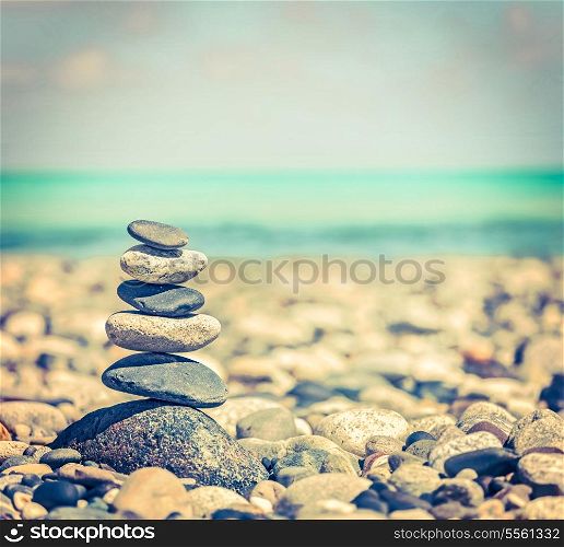 Vintage retro hipster style travel image of Zen meditation background - balanced stones stack close up on sea beach
