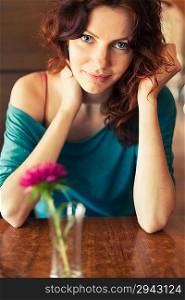 Vintage Retro look Redhead women sitting in the cafee with pink flower on the table befor and looking at camera and smiling