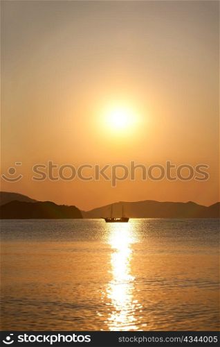 Vintage sailboat sailing in the sea at sunrise