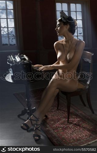 vintage shot of a naked woman sitting on desk and typing on an old fashion type-writer in dark background