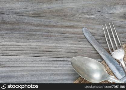 Vintage spoon, knife and fork are on the old weathered boards