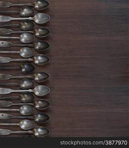 Vintage spoons border on the old dark wooden board
