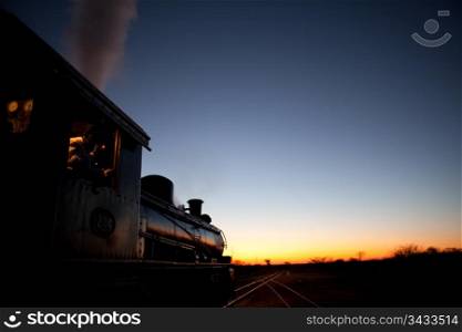 Vintage steam locomotive pointed into the sunset