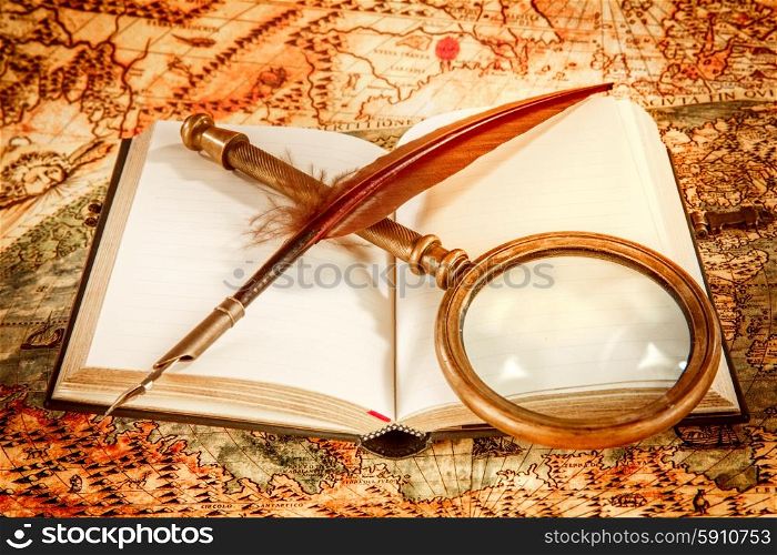 Vintage still life - magnifying glass, old book and goose quill pen lying on an old map in 1565.