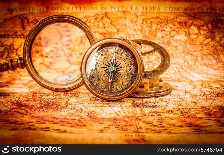 Vintage still life. Vintage magnifying glass and compass lies on an ancient world map in 1565.