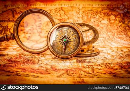 Vintage still life. Vintage magnifying glass and compass lies on an ancient world map in 1565.