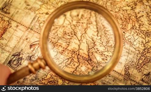 Vintage still life. Vintage magnifying glass lies and compass on ancient world map in 1565.
