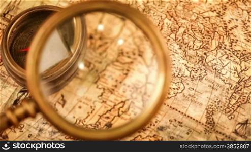 Vintage still life. Vintage magnifying glass lies and compass on ancient world map in 1565.