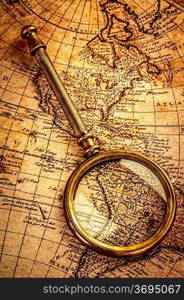 Vintage still life. Vintage magnifying glass lies on an ancient world map