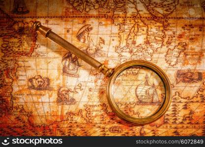 Vintage still life. Vintage magnifying glass lies on an ancient world map in 1565.