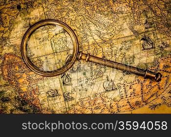 Vintage still life. Vintage magnifying glass lies on an ancient world map of 1565.