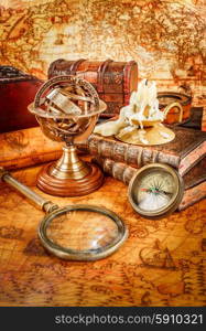 Vintage still life. Vintage magnifying glass lies, pocket watch, old book and armillary sphere on an ancient world map in 1565.