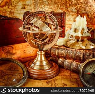 Vintage still life. Vintage old book and armillary sphere on an ancient world map in 1565.