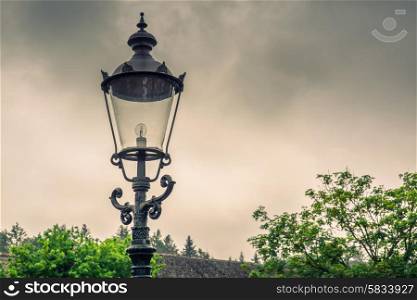Vintage street lamp with a bulb in cloudy weather