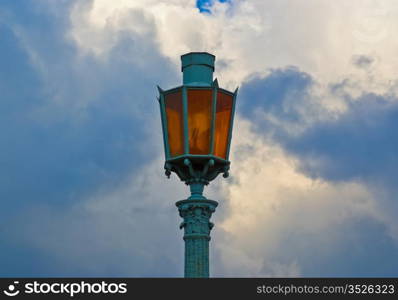 vintage street lamp with orange glass on cloud sky background