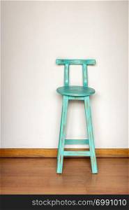 Vintage style blue wooden stool against a plain white wall