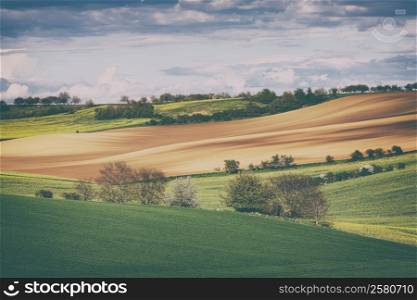 Vintage style image of rolling hills and fields at sunset