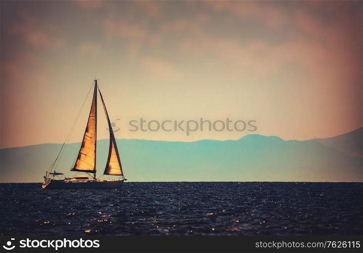 Vintage style photo of a beautiful sailboat in the distance floating in the sea, luxury water sport, wonderful summer adventure