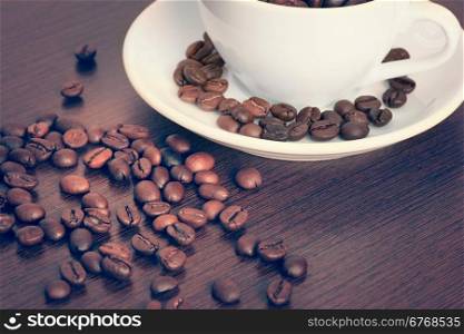 Vintage style photo of cup of coffe beans on a table