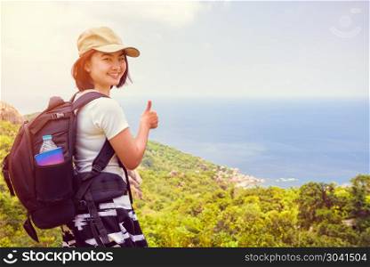 Vintage style women at Koh Tao. Vintage style women tourist with a backpack wear cap raise thumbs up for the beautiful nature landscape blue sea and sky from high scenic viewpoint at Koh Tao, Surat Thani, Thailand