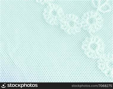 Vintage textile background - fragment of white lace fabric with a floral pattern on a light turquoise background closeup. Selective soft focus. . Fragment Of A Pastel Floral Lace Background