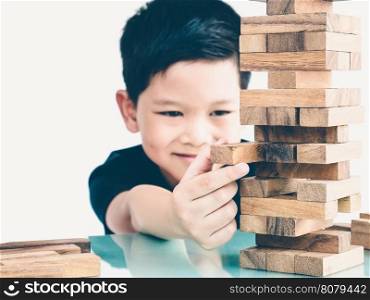 Vintage tone of asian kid is playing wood blocks tower game for practicing physical and mental skill. Photo is focused is hands.