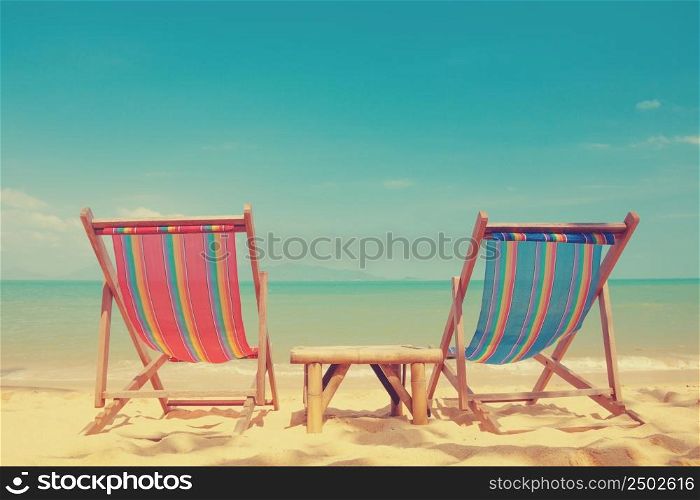 Vintage toned two beach chairs on tropical shore