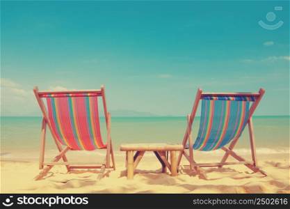 Vintage toned two beach chairs on tropical shore
