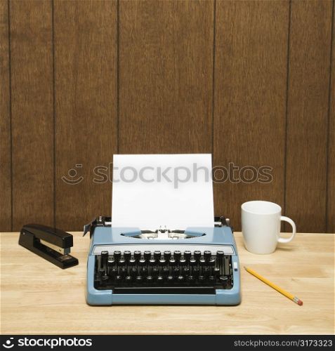 Vintage typewriter, coffee cup, pencil and stapler on desk.