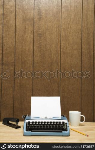 Vintage typewriter, coffee cup, pencil and stapler on desk.