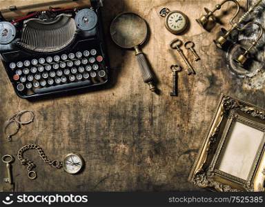 Vintage typewriter, golden frame, old office accessories on wooden table. Nostalgic still life
