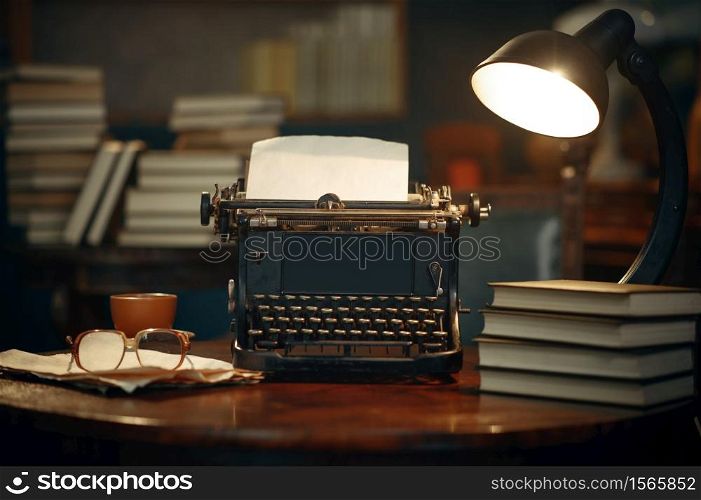 Vintage typewriter on wooden table in home office, nobody. Writer workplace in retro style, cup of coffee and glasses. Vintage typewriter on wooden table in home office