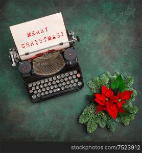 Vintage typewriter with Christmas decoration and red poinsettia flowers. Merry Christmas! Vintage style toned picture