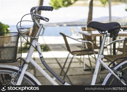 Vintage white bicycle. Cafe tables on background