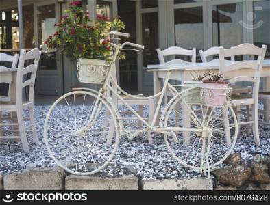 Vintage white bicycle. Cafe tables on background. Greece, Gythio