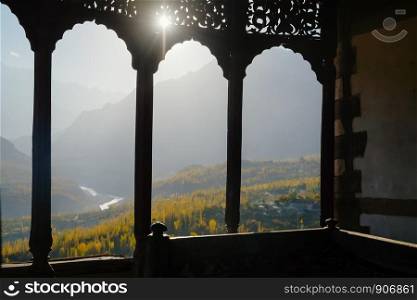 Vintage window of Baltit fort with a blurry landscape view of Hunza Nagar valley and Karakoram mountain range in the background. Karimabad Gilgit Baltistan, Pakistan. Selective focus.