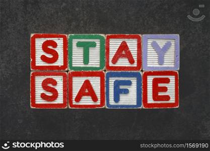 vintage wooden alphabet letter block kid toy spelling STAY SAFE on dark texture background for COVID 19 idea concept, text, cube, dice, crossword