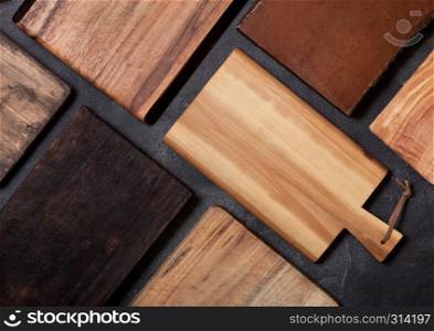 Vintage wooden cutting boards different shape on top of black stone kitchen stone background. Top view.