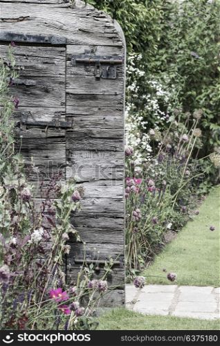 Vintage wooden garden door opwening into beautiful Summer garden full of flowers with secret garden feel to the image