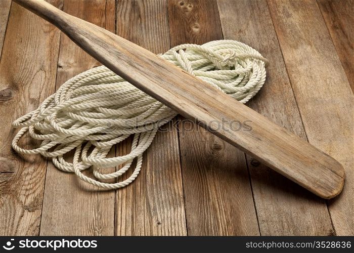 vintage wooden oar and and coiled rope on a wood deck