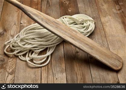vintage wooden oar and and coiled rope on a wood deck
