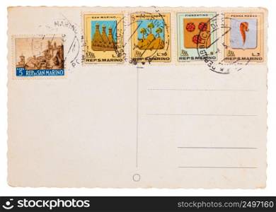 Vintage yellowed postcard with post meter stamps and different old stamps from San Marino isolated on white