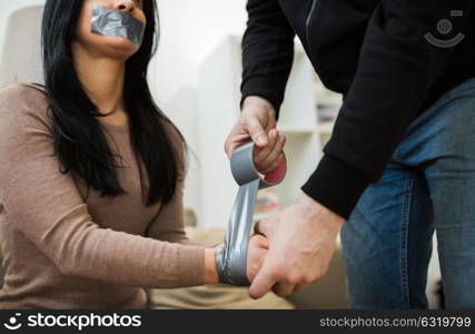 violence, crime, kidnapping and people concept - criminal tying woman hands with adhesive tape. criminal tying woman with adhesive tape